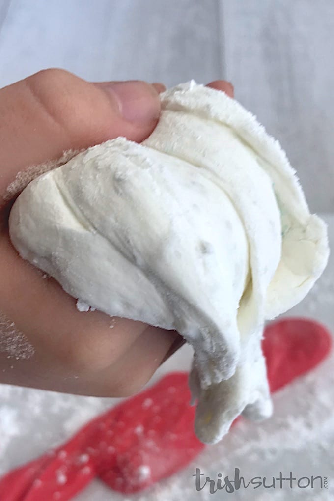 A hand holds a bunch of white fluffy slime.