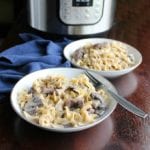 two bowls of creamy beef stroganoff with an instant pot in the background