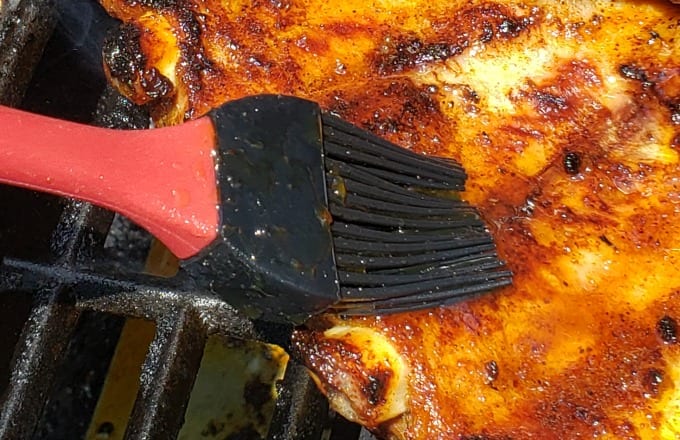 The Best Way to Grill Ribs is to slather it with a glaze at the end. Here a basting brush adds apricot glaze to pork ribs.