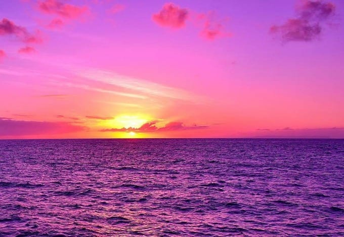 A Kauai Sunset Cruise is never quite the same twice. Here the yellow sun colors the sky pink as it sinks down into the ocean.