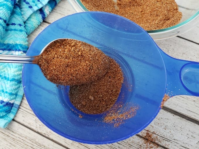 Spoonful of seasoning mix hovering over a jar funnel.