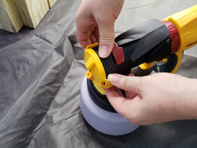 Woman demonstrating how to use a paint sprayer.