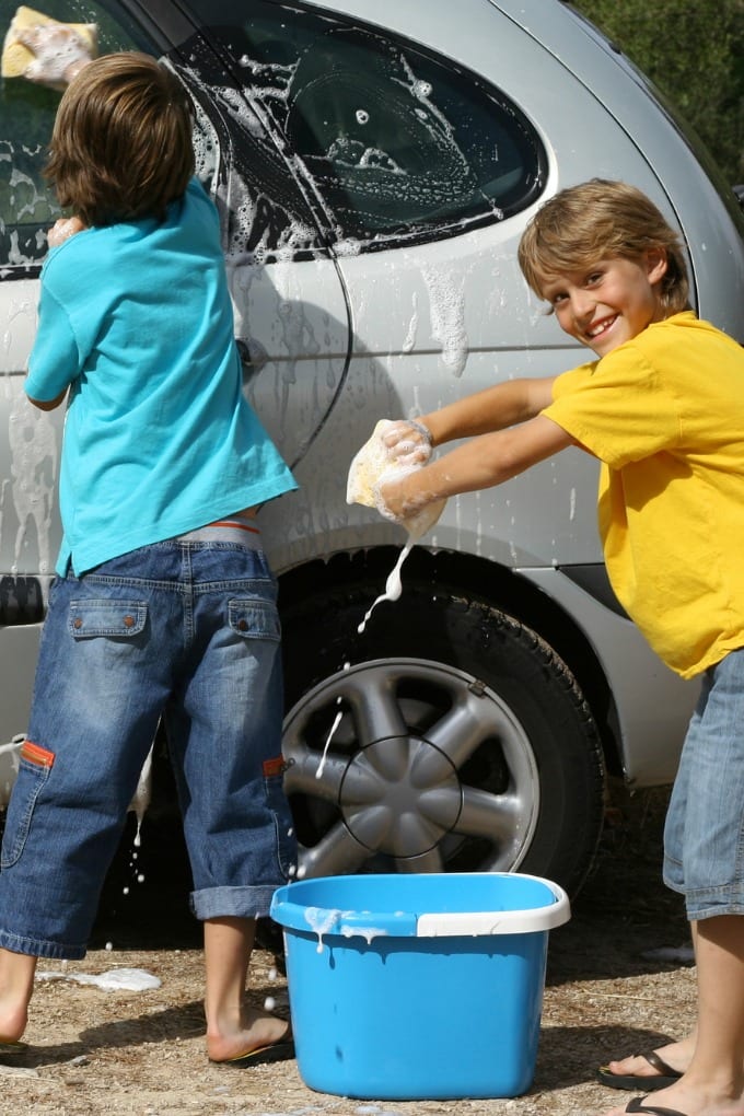 Two kids washing a car