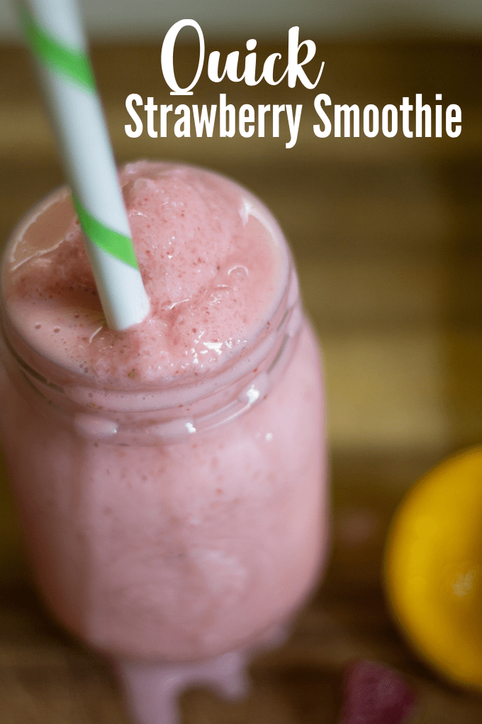 strawberry smoothie in glass jar will a cut lemon on the side