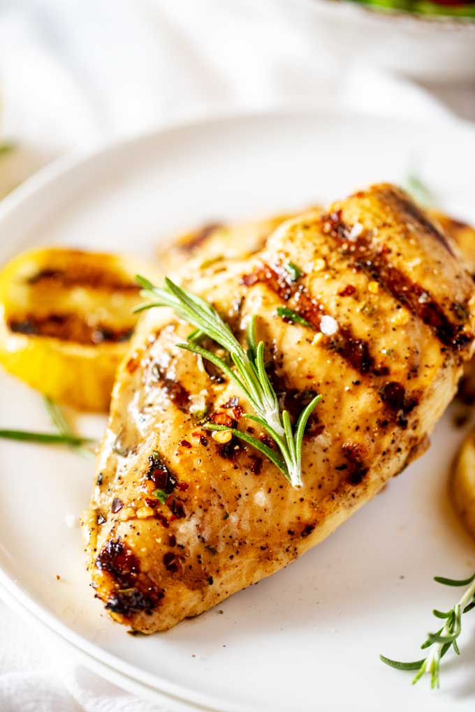 Close up photo of Grilled Lemon Pepper Chicken on a white plate.