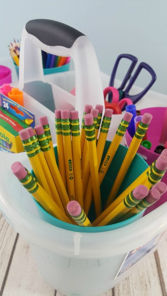 A close up of pencils in a clear plastic caddy with other school supplies.