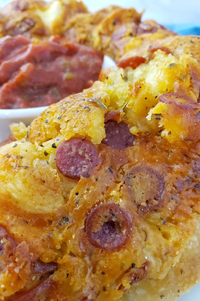Close up of Pull Apart Pizza Bead on white plate next to a ramekin of marinara sauce.