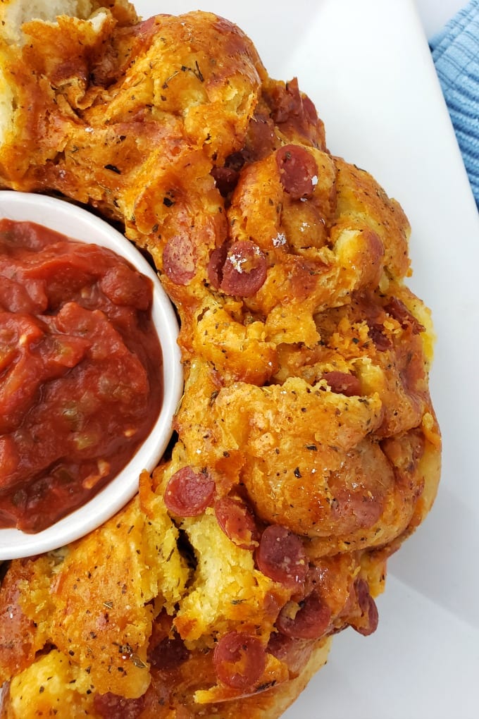 Pizza monkey bread on a white plate next to a bowl of marinara sauce.