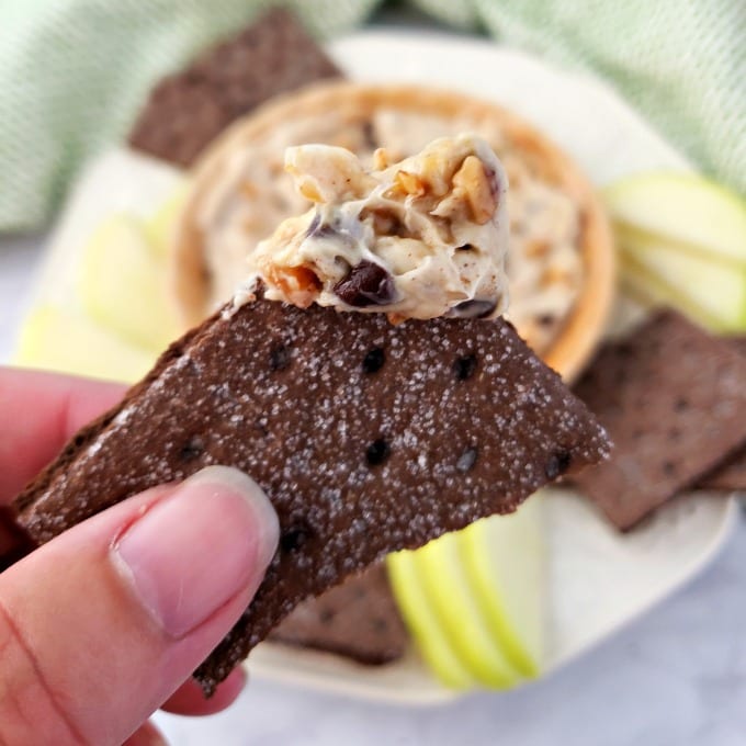 Fingers holding a chocolate graham cracker with toffee apple dip.