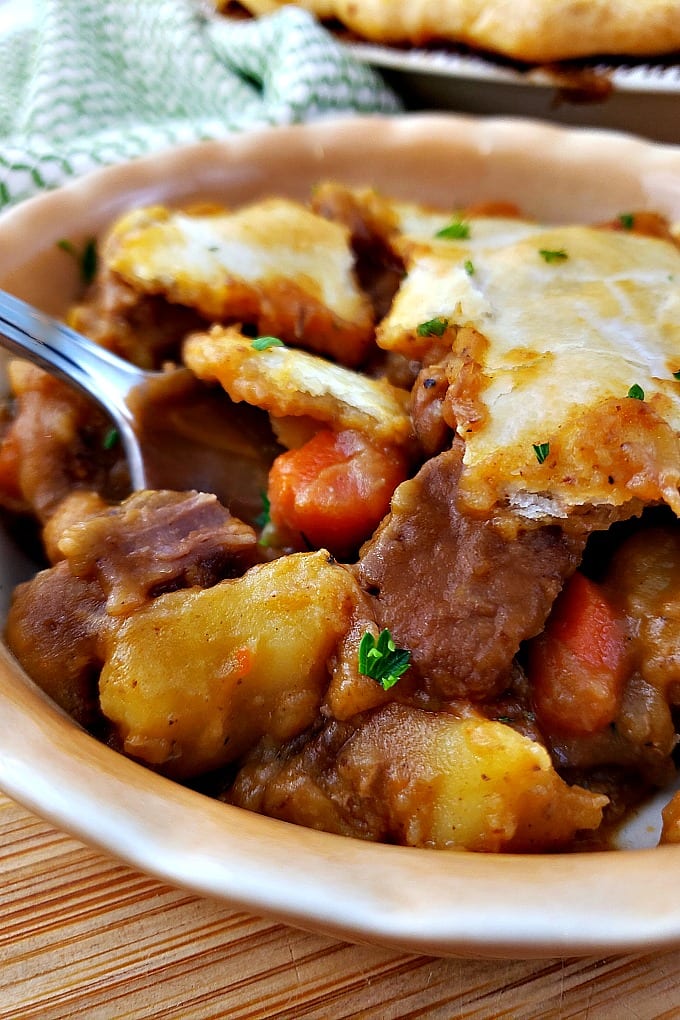 Close up of homemade beef pot pie in a bowl with a spoon.