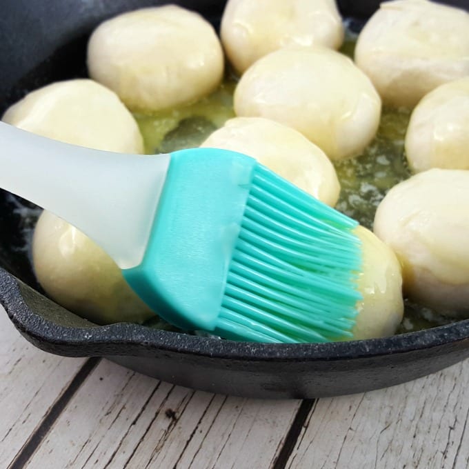frozen dinner rolls and melted butter in a cast iron skillet and a pastry brush.