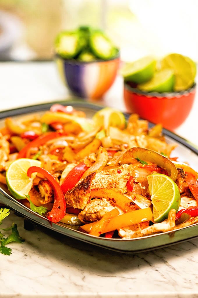 Platter of fajitas with lime and jalapeños