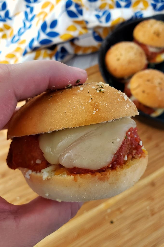 A hand holds a meatball slider