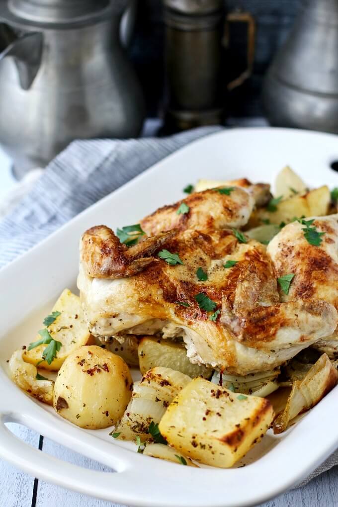 Spatchcocked chicken on a serving platter with roasted potatoes