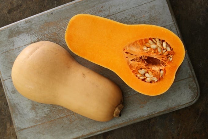 Butternut squash cut in half on a cutting board.