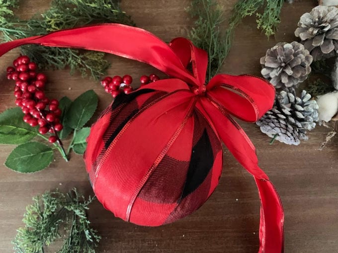 Top down image of a foam ball covered with buffalo check fabric with a red ribbon tied to  it. 