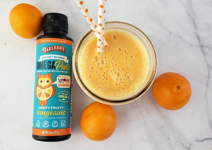 Top down view of a clementine smoothie in a mason jar next to fresh clementines.