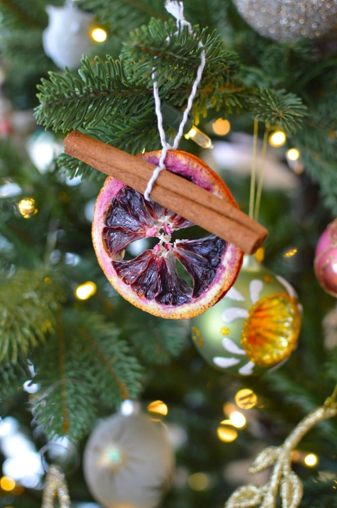 Dried orange ornament with cinnamon stick on a Christmas tree.