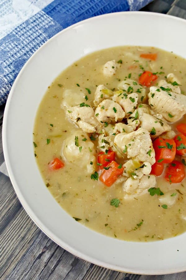 How to Make Chicken and Dumplings with Biscuits - close up of a bowl of chicken and dumplings with carrots garnished with parsley