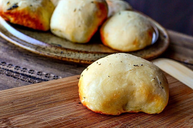 Close up of a stuffed pizza roll on a cutting board.