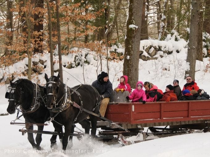many people enjoying a ride on a big red sled pulled by horses through the snow.