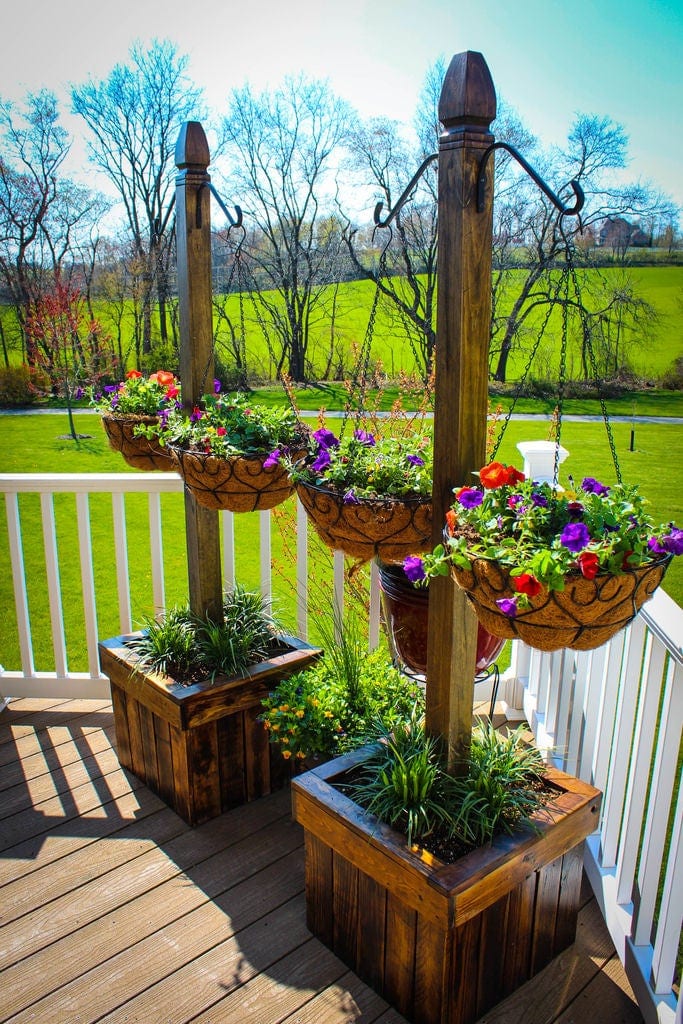 DIY planter boxes made from pallets with added hanging plant hooks on a tall post.