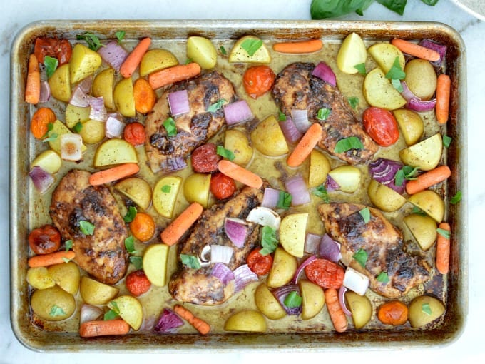 Top down view of a Sheet Pan with Balsamic Chicken, golden potatoes, red onions, tomatoes and carrots.