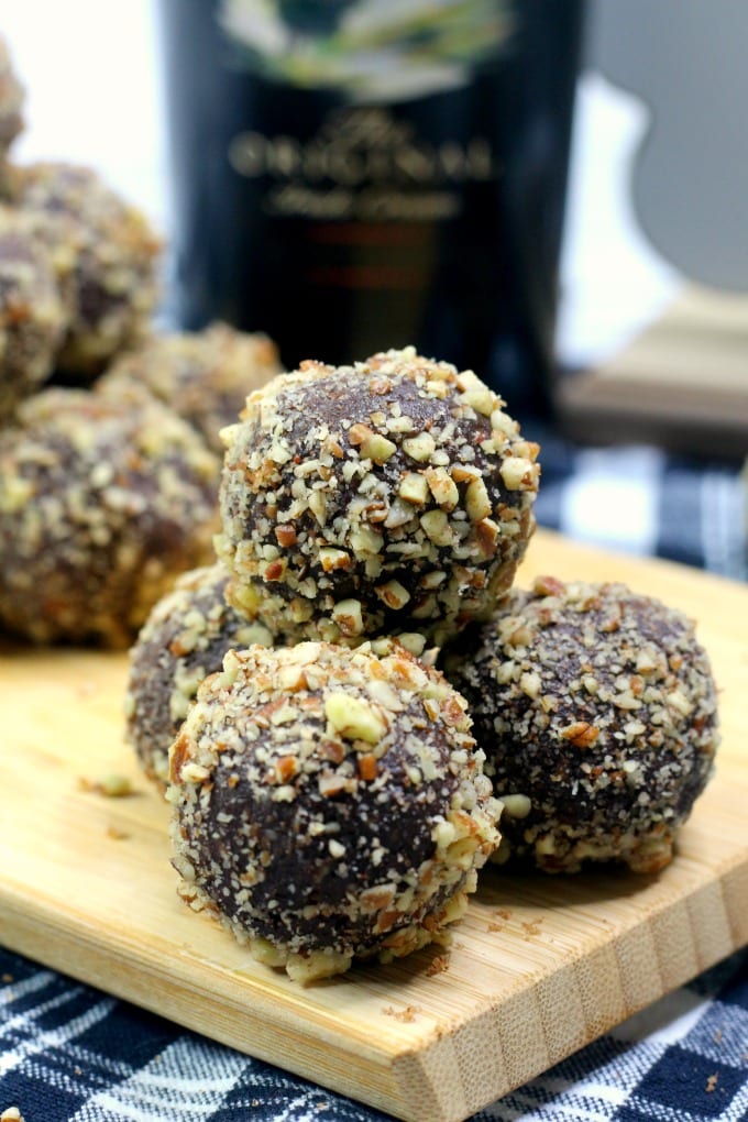 close up of Baileys Chocolate Truffles on a cutting board with a bottle of Irish Cream liquor in the background.