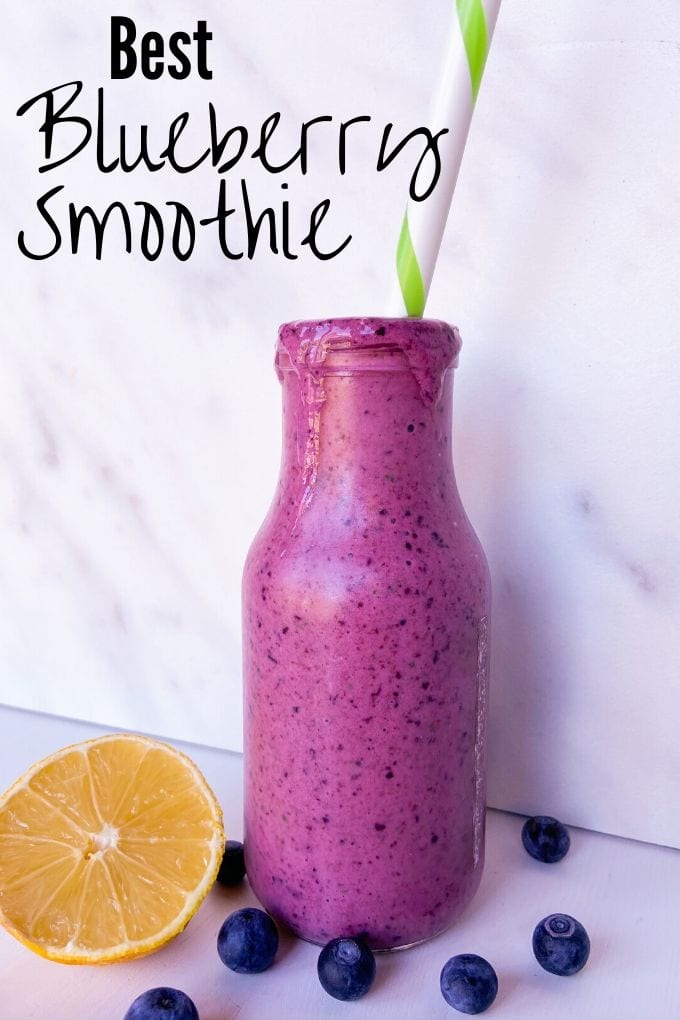 Blueberry smoothie in a glass jar with blueberries and a lemon half.