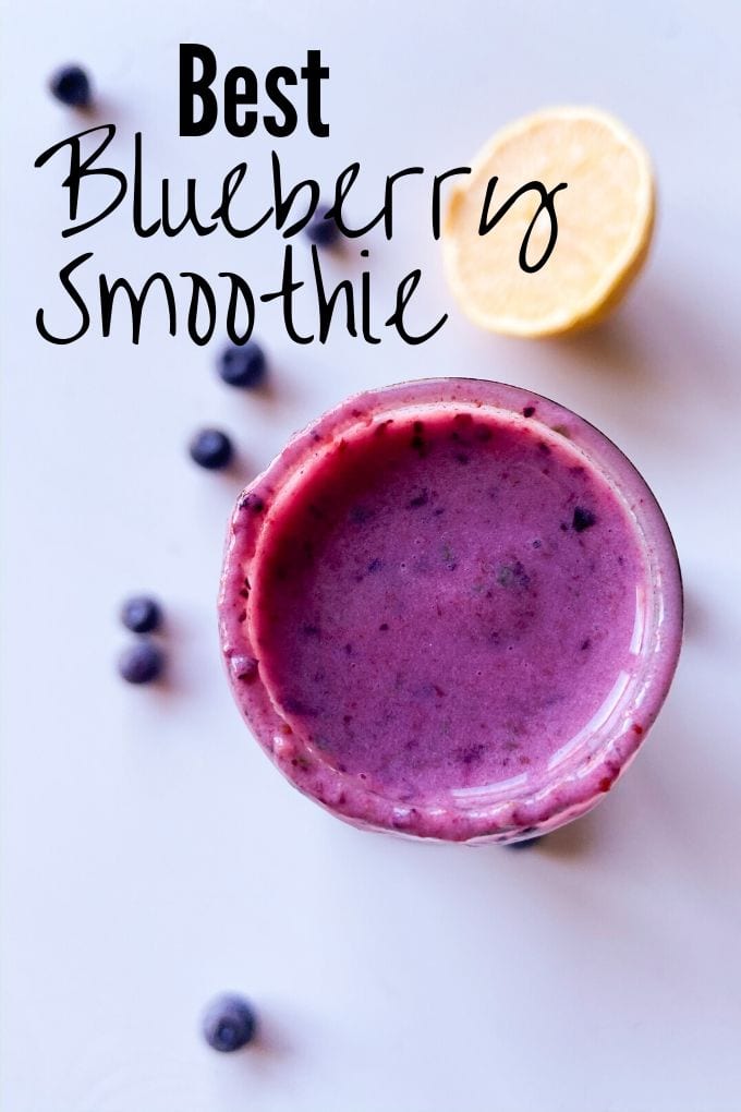 Top of a jar full of blueberry smoothie with half a lemon and blueberries around it