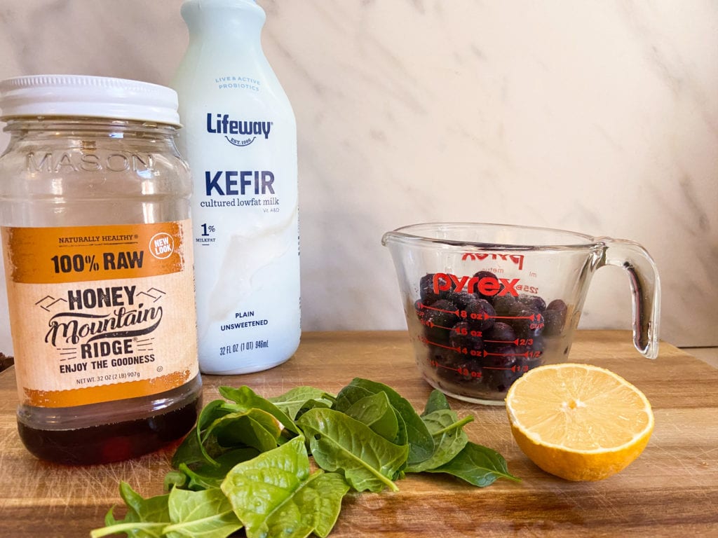 honey, kefir, blueberries, spinach, and lemon on wooden cutting board