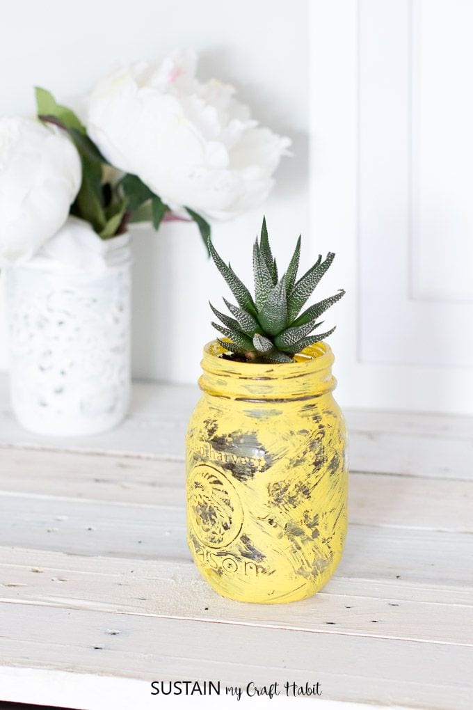 mason jar painted yellow iwht succulents growing out of it