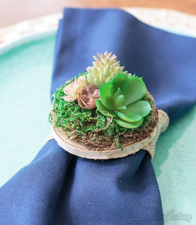 close up of a succulent napkin ring ona blue cloth napkin