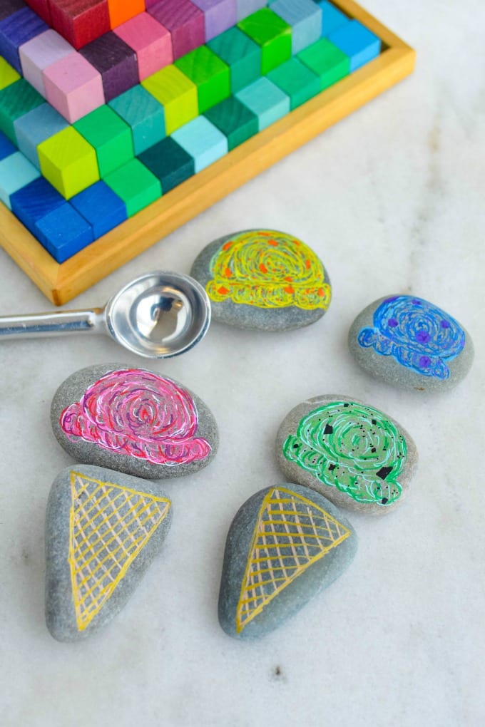 Smooth gray rocks with ice cream cones and ice cream scoops painted on them, surrounded by blocks and an ice cream scooper.
