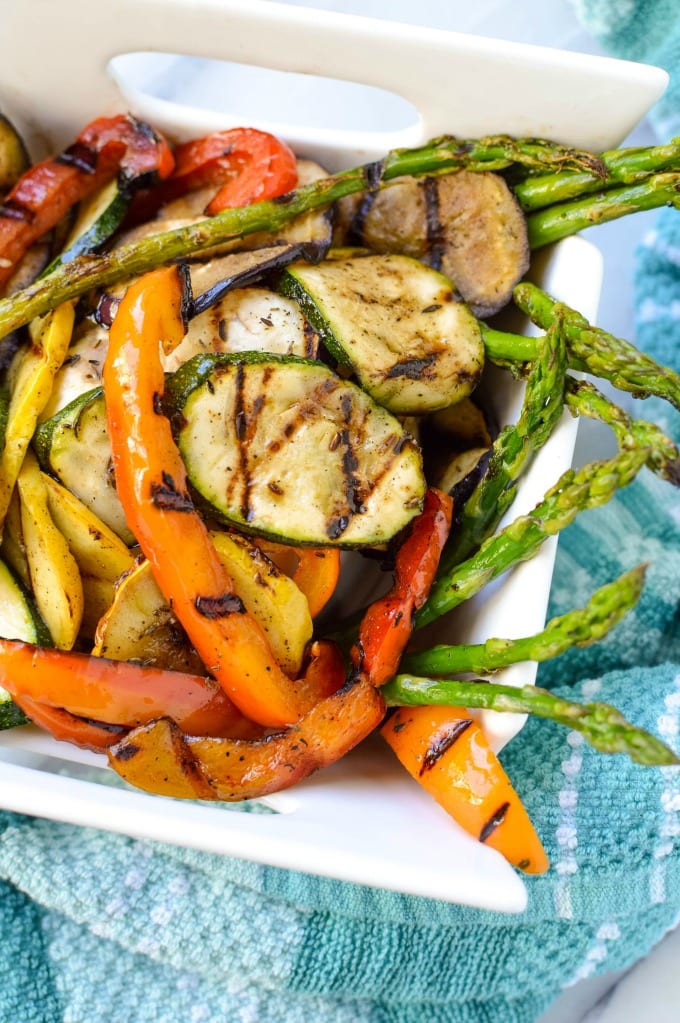 Mediterranean grilled vegetables:  grilled zucchini, bell peppers, and asparagus in a white ceramic dish.