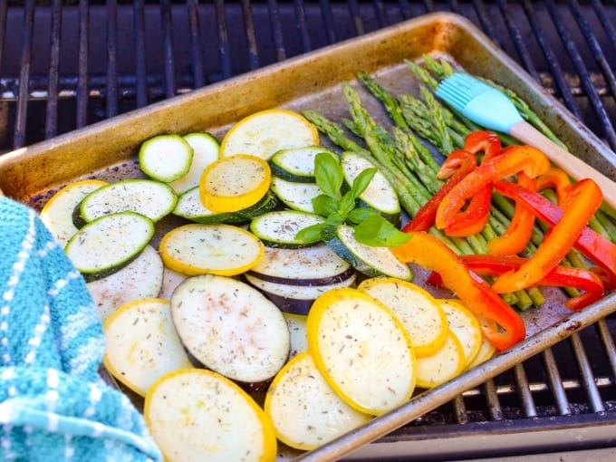 Mediterranean Grilled Vegetables - zucchini, squash, peppers and asparagus, on a metal sheet pan on a grill.