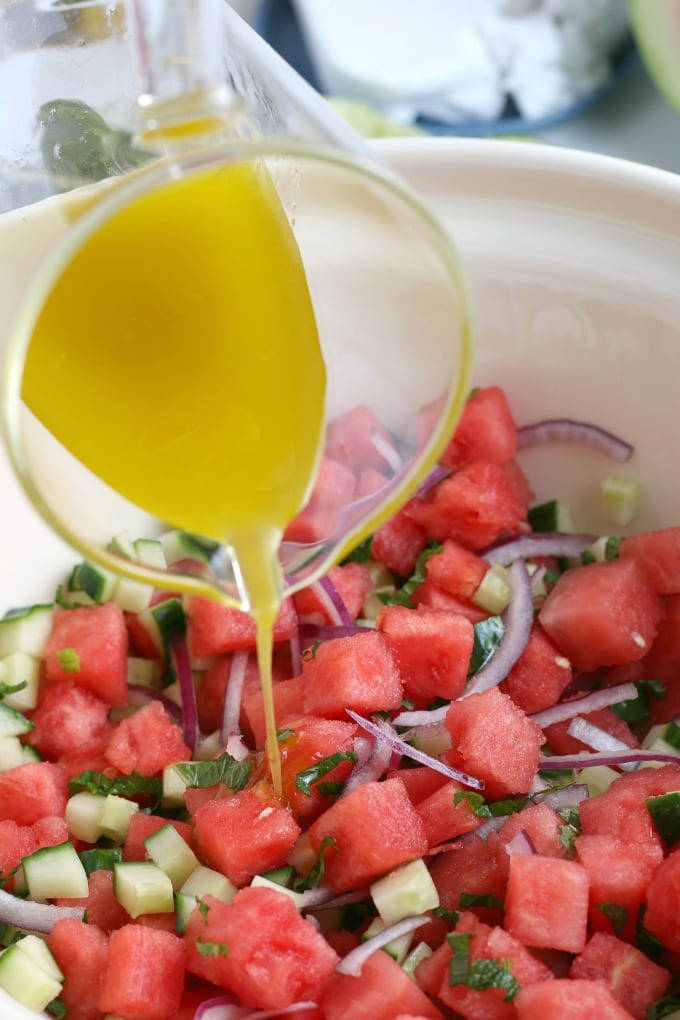 Watermelon salad being dressed from measuring cup above.