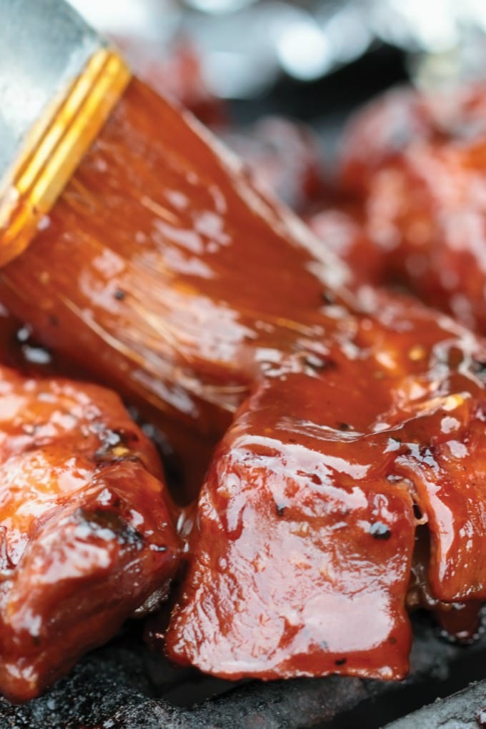 Image of ribs on the grill be brushed with Cherry BBQ Sauce.