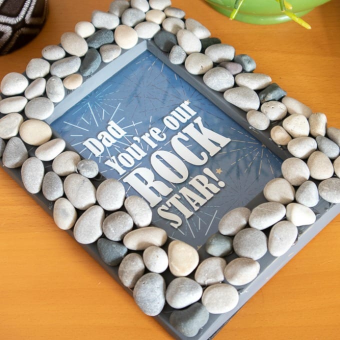 Finished Cricut Photo Frame covered in rocks laying on a table top.