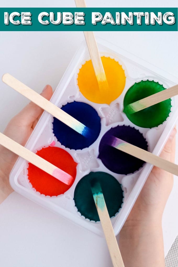 Painting with Ice Cubes- Child's hands holding an ice cube tray with water dyed with food coloring to make painting craft sticks.
