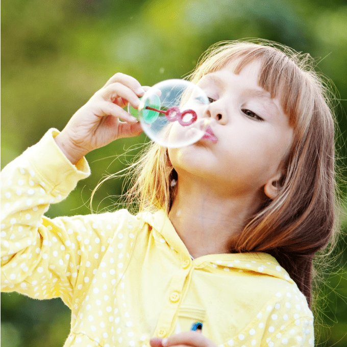 Young girl blowing bubbles.