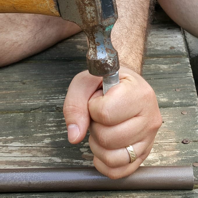 Hammer and hand holding a nail punch.