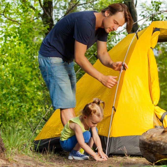 backyard camping ideas - dad and little girl setting up a yellow tent for camping