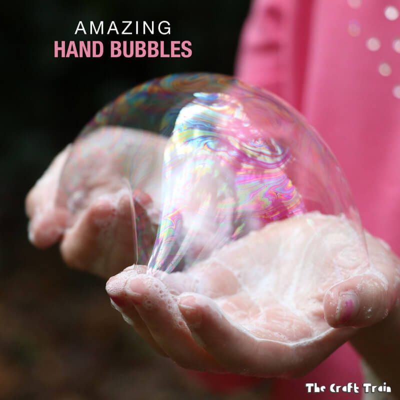 Bubbles and suds sitting on a child's hands.