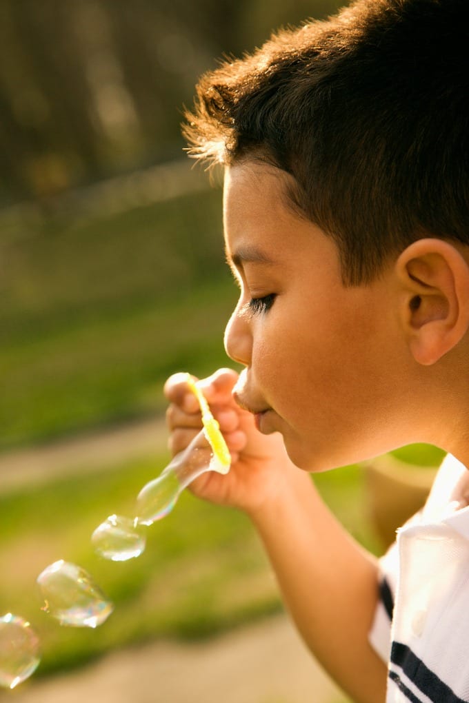Young boy blowing bubbles outside. 