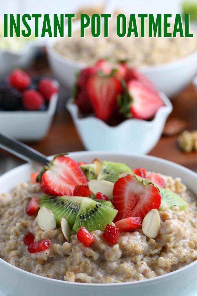 A bowl filled with oatmeal and topped with fresh strawberries, kiwi, and nuts.