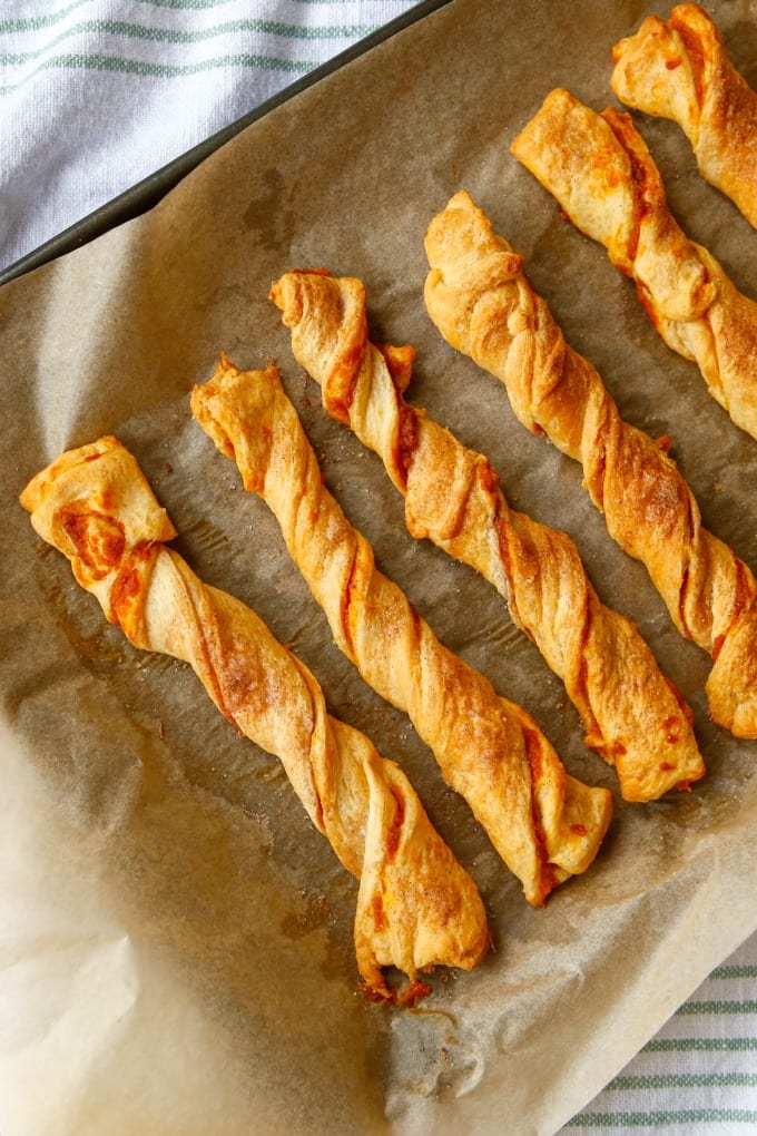 Pumpkin spice puff pastry twists on a parchment lined baking sheet.