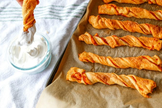 Pumpkin spice puff pastry twists on a parchment lined baking sheet.