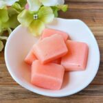 Square image of several sugar scrub bars in a small white bowl.