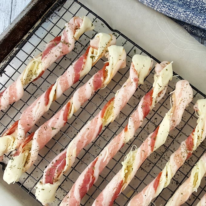 How to make bacon puff pastry twists: bacon wrapped puff pastry with parmesan cheese on a baking sheet.